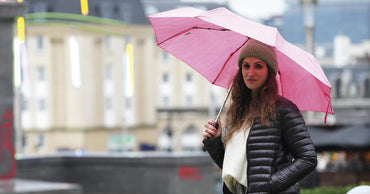 Femme sous un parapluie rose clair Parfi, marque belge de parapluies raffinés et stylés.