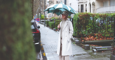 Femme tenant un parapluie vert et blanc original signé Parfi, marque belge de parapluies élégants.