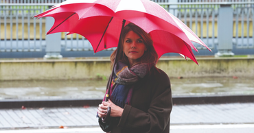 Femme sous un parapluie rouge Parfi, une marque de parapluies belges de qualité, design chic pour affronter la pluie.
